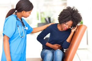 young african nurse comforting female patient in doctors office