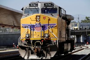 FILE PHOTO: A GE AC4400CW diesel-electric locomotive in Union Pacific livery, is seen ahead of a possible strike if there is no deal with the rail worker unions, as a Metrolink commuter train (right) arrives at Union Station in Los Angeles, California, U.S., September 15, 2022. REUTERS/Bing Guan/File Photo