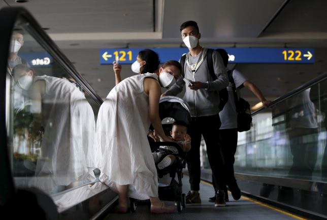 Passengers wearing masks to prevent contracting Middle East Respiratory Syndrome (MERS) ride on a travelator upon arrival at Incheon International Airport in Incheon, South Korea, June 2, 2015. REUTERS/Kim Hong-Ji